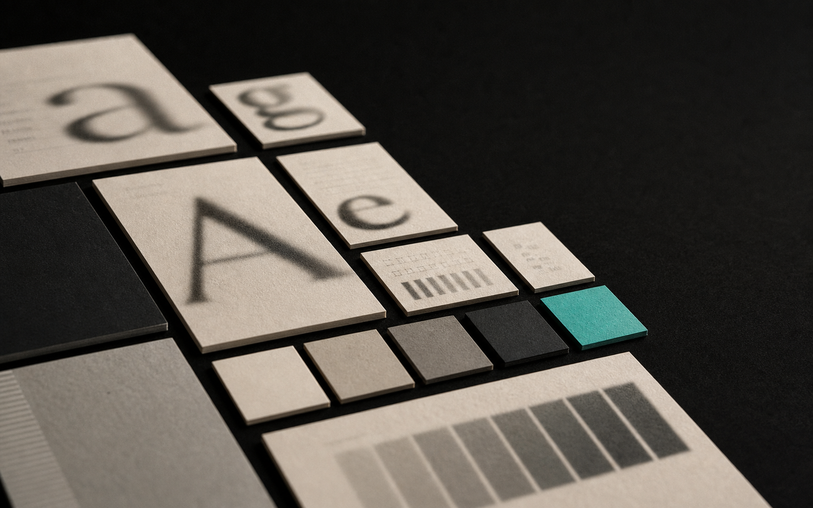 A systematic grid of cream paper type-specimen cards and color swatch chips, mostly neutral with exactly one teal chip standing out.